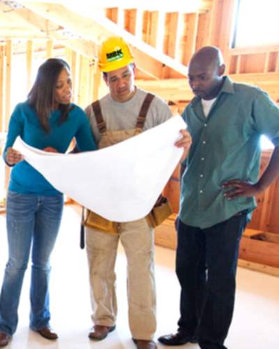 An image of a black couple looking at blueprints with a MBK building engineer inside a home going through a whole home remodeling project.