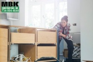 an image of a woman carpenter and she looks very focused on building a counter during a kitchen remodel.