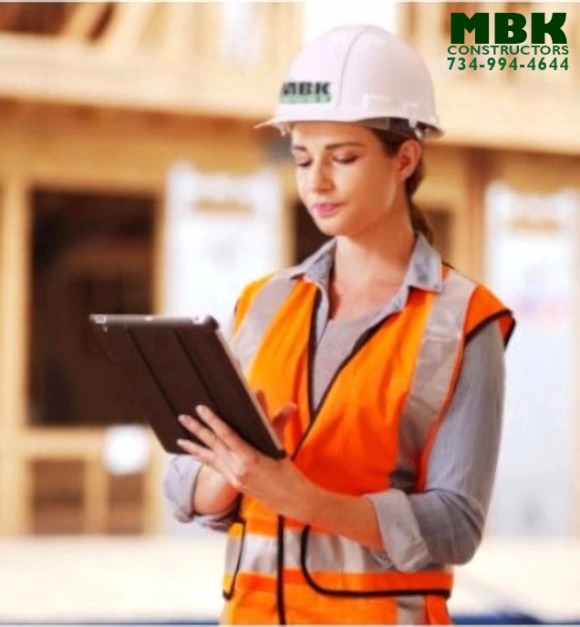 an image of a woman standing in front of a construction site. She is typing something into her tablet, she is the site manager, and it looks like a warm sunny summer day
